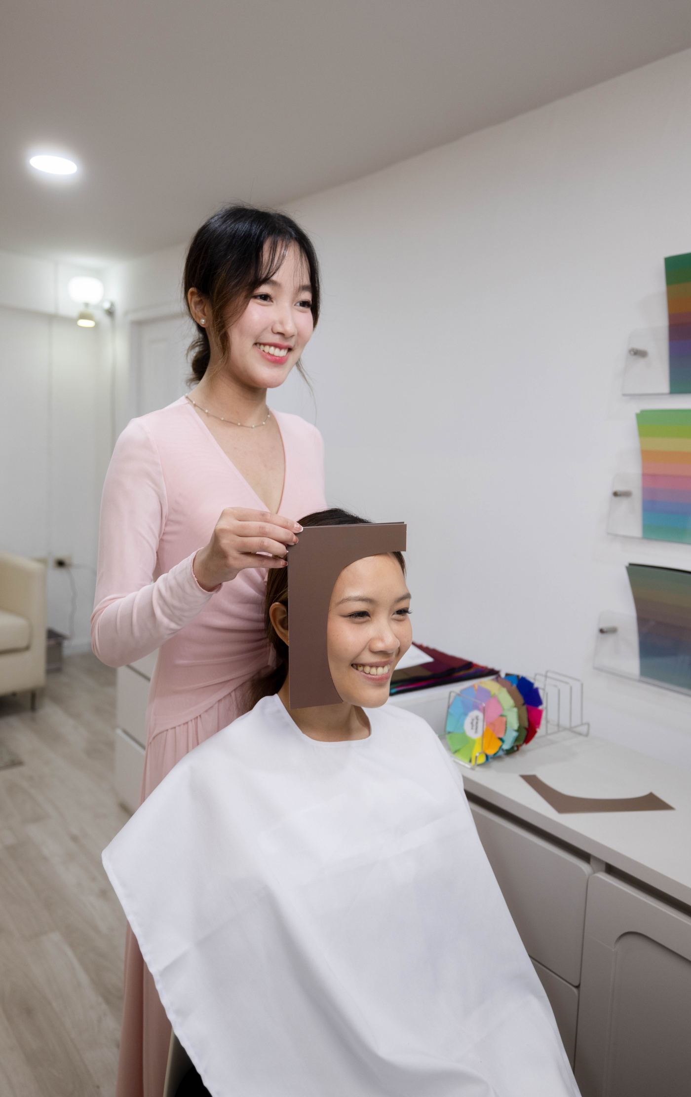 A consultant testing a hair color swatch against a client's hairline at Soori Studio