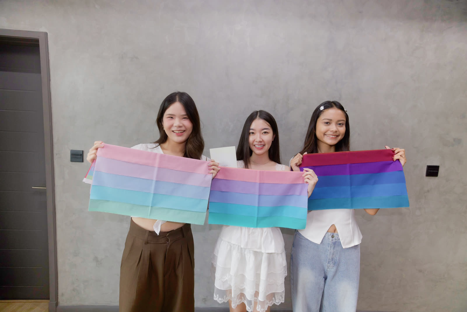 Three clients holding up their personal color drapes after a group session