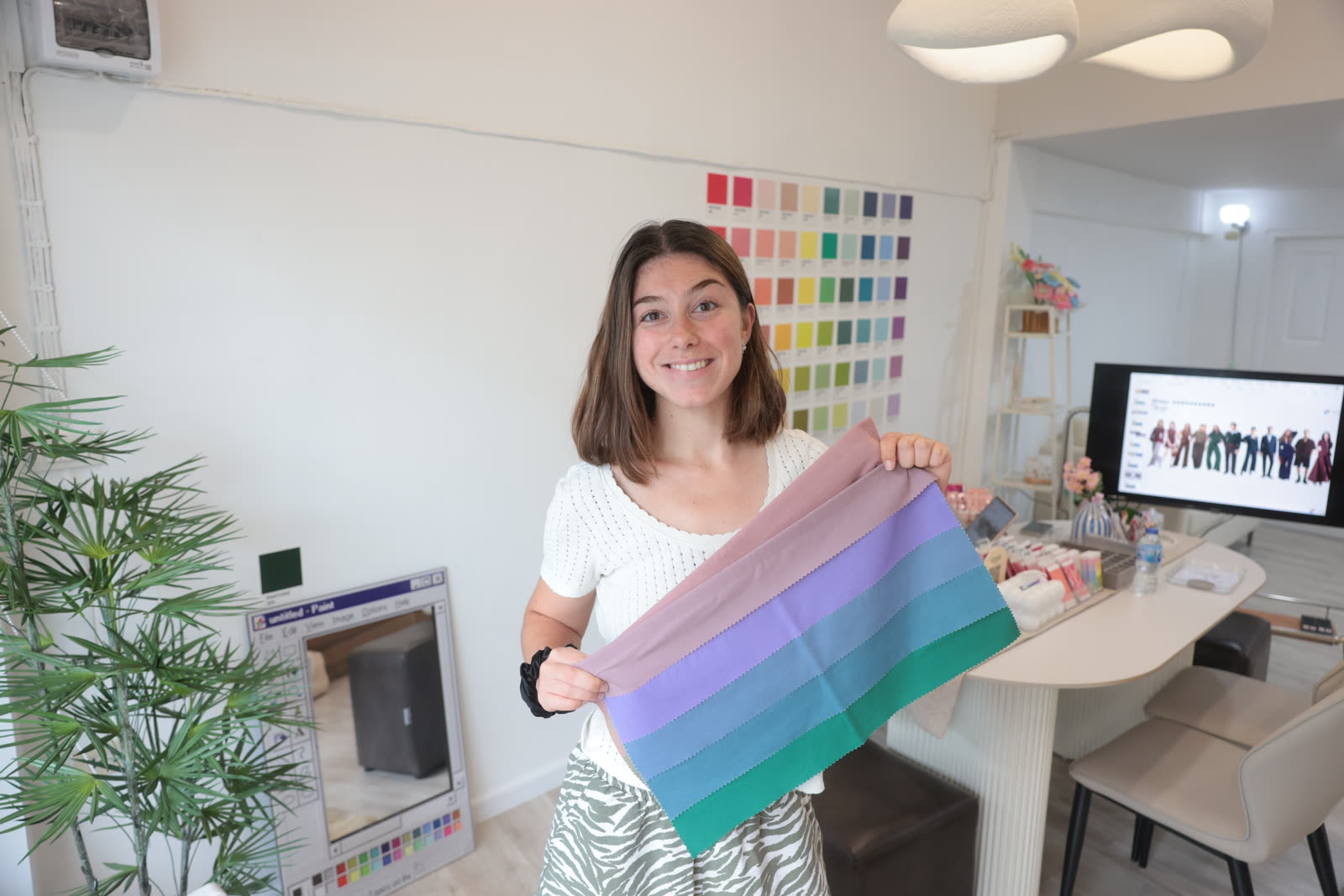 Client smiling while holding her cool pastel color drape fan at Soori Studio